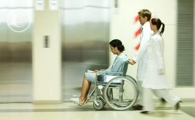 Hospital_staff_pushing_man_in_wheelchair_blurred_PAA451000001.jpg